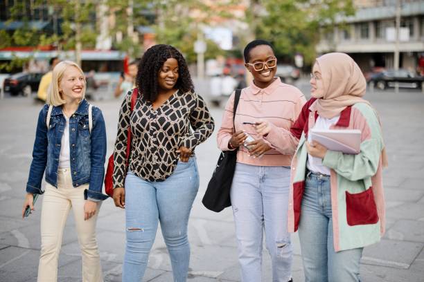 istock Four girl friends walk the city streets and chat 1340214432