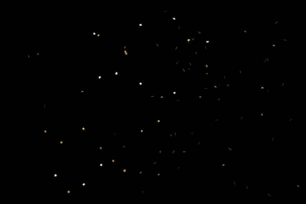 confettis en forme d’étoile tombant sur fond noir - confetti gold black star shape photos et images de collection