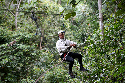 A Muslim man is enjoying extreme game. He is pulling before reaching destination in flying fox activity.