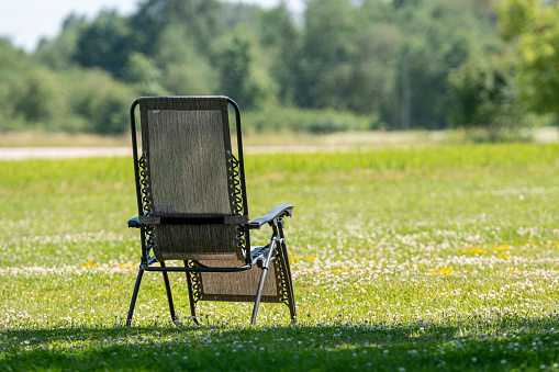 empty folding garden chair on the yard lawn of a country house on a sunny day