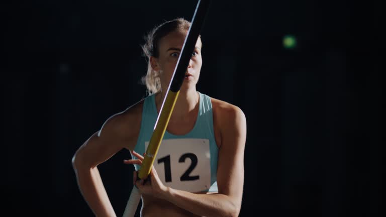 Pole Vault Jump Championship: Portrait of Professional Female Athlete Running with Pole. Determination, Motivation, Effort of Champion in Training. Dramatic Light, Slow Motion Sport. Medium Shot