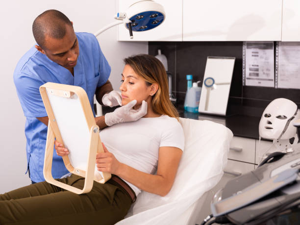 istock Cosmetologist examining female client face before procedure 1340218353