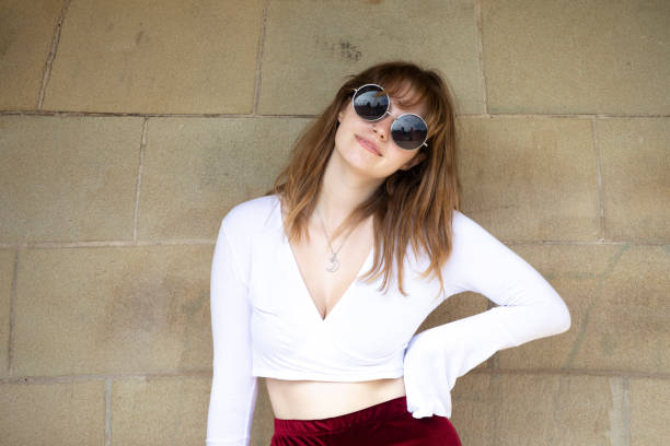 istock Fashionable young woman standing by a stone wall and looking at the camera 1340218768
