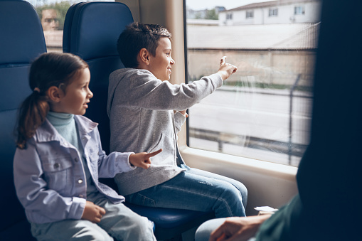 Two happy little kids enjoying train journey with family