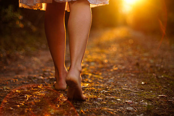 View of young woman's legs walking on dirt path stock photo