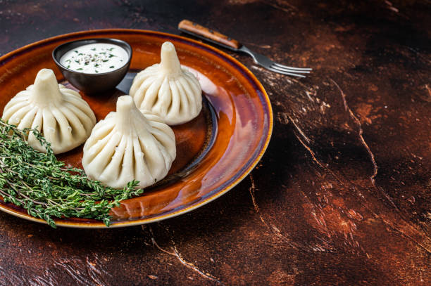 istock Khinkali Dumplings with beef and lamb meat on rustic plate with herbs. Dark background. Top view. Copy space 1340221641