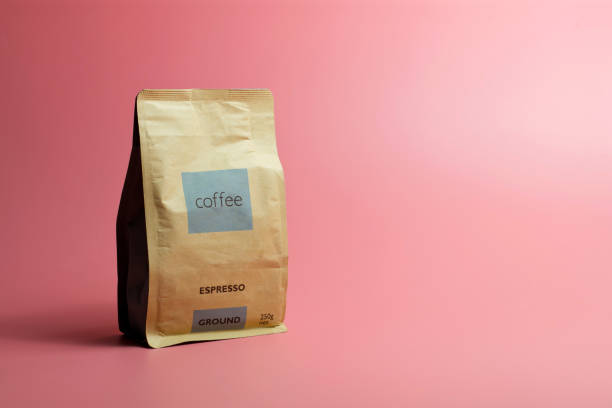 un sacchetto di carta in grani di caffè su sfondo rosa - coffee bag foto e immagini stock