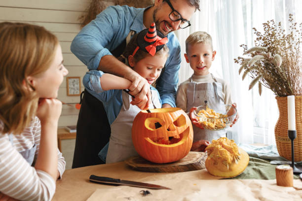 istock Father helping  daughter to remove pulp from from pumpkin while carving jack o lantern with family 1340223118