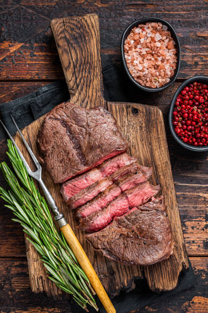 Fried Top Blade or flat iron roast beef meat steaks on wooden board with rosemary. Dark wooden background. Top View Fried Top Blade or flat iron roast beef meat steaks on wooden board with rosemary. Dark wooden background. Top View. blade roast stock pictures, royalty-free photos & images