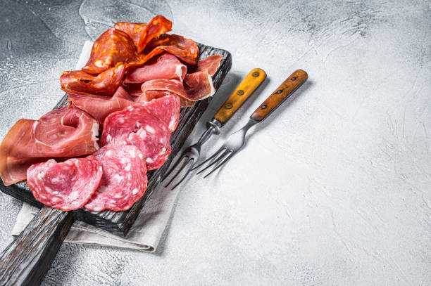 istock Assorted meat appetizers - salami, jamon, choriso sausages. White background. Top view. Copy space 1340229408