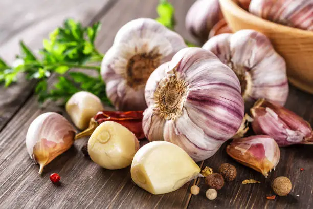 Photo of Closeup of Garlic bulbs on wooden table with garlics blur background.A set of fresh garlic on the chest wooden background.
