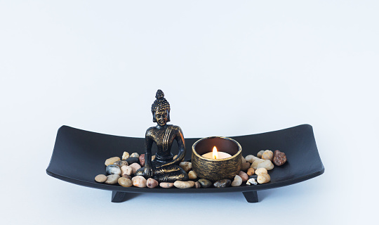 Altar with Buddha statue, burning candle and pebbles. Meditation, buddhism and enlightenment concept