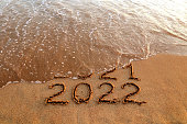 New year 2022 and 2021 on sandy beach with waves