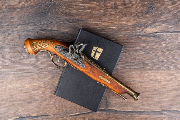 istock Model old retro muzzle loader flintlock pistol on top of a bible on a wooden table. 1340233145