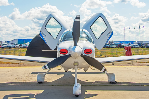 Light-engine turboprop aircraft with open doors stands in the parking lot of the airfield, front view
