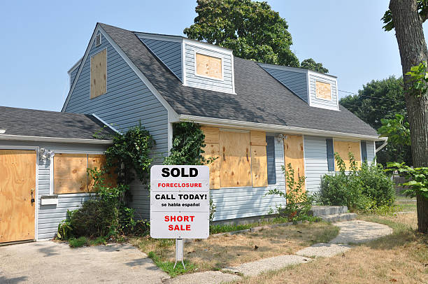 istock Real Estate Agent Foreclosure Sign on Abandoned Cape Code Suburban Home Lawn 134023570
