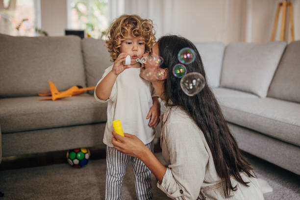 mom and son blowing bubbles at home - bubble child bubble wand blowing imagens e fotografias de stock