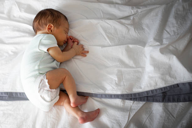 Newborn sleeping in parents bed, lying on side. Copy space.