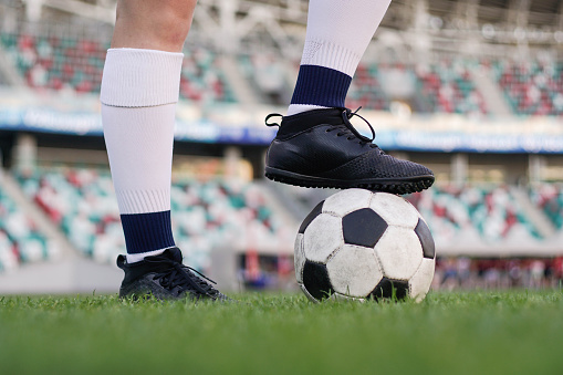 Legs of a female football player on soccer ball at stadium, close up