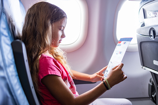 Girl looking at safety instruction card in the plane