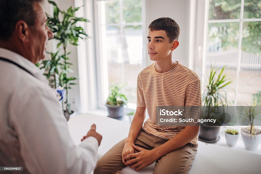 Oberarzt spricht mit jugendlichem Patienten im medizinischen Untersuchungsraum - Lizenzfrei Teenager-Alter Stock-Foto