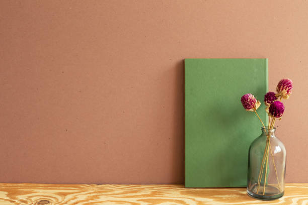 green notebook and dry flowers on wooden desk. brown wall background. copy space - globe amaranth imagens e fotografias de stock