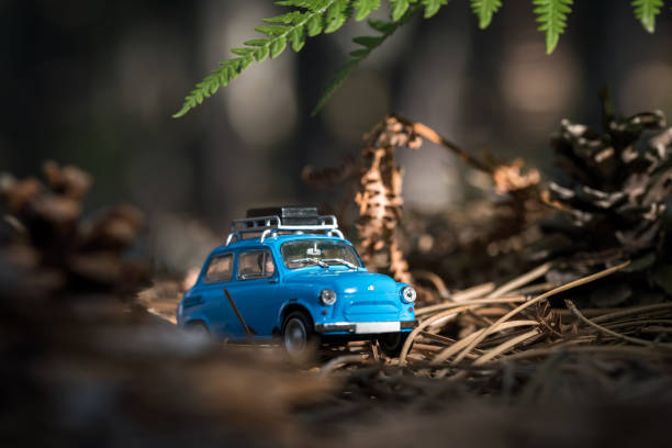 istock Cute little nonexistent retro car with luggage on top on a forest road 1340253094