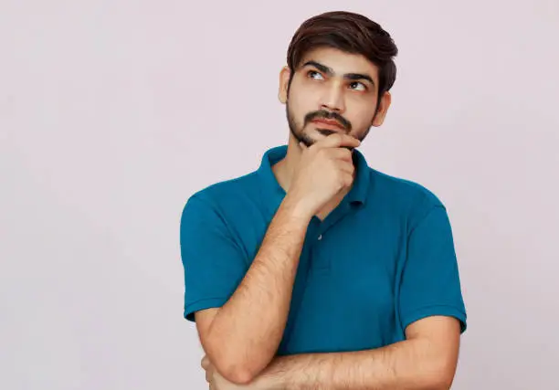 Young man with blue shirt thinking expression on isolated background.