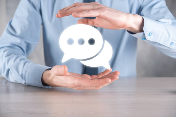 istock Businessman holding a message icon, bubble talk notification sign in his hands. Chat icon, sms icon, comments icon, speech bubbles 1340254001