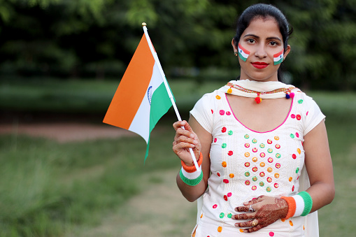Smiling young woman with holding tricolor Indian flag in hand on Independence day, 15, August, India.
