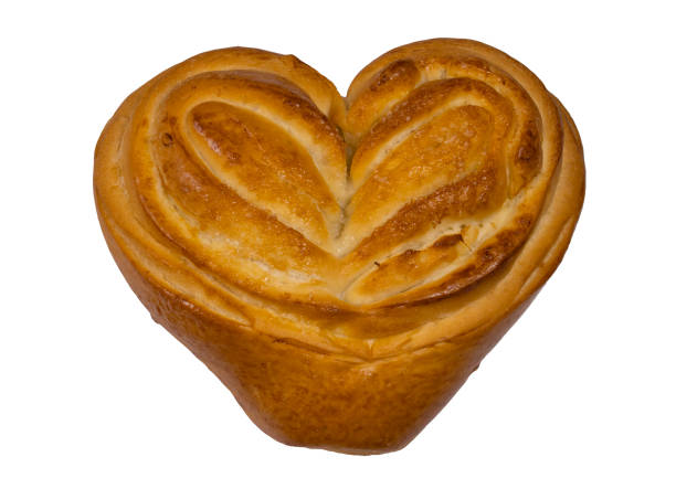 A bun in the shape of a heart. Top view. A bun isolated on a white background. Fresh bun with sugar. Delicious dessert. Confectionery product.