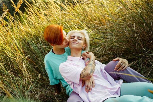 Lesbian lady intimates kissing with girlfriend on meadow stock photo