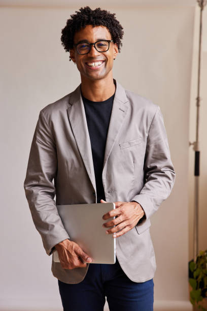 istock Young businessman with a laptop smiling against a gray backdrop 1340258845