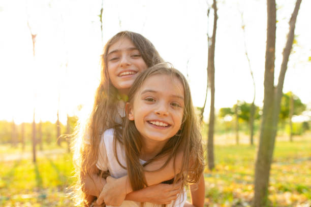 две маленькие сестры в парке солнечным осенним днем. семейное время. - peoples park стоковые фото и изображения