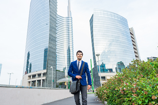 Portrait of confident young entrepreneur standing in front of corporate buildings