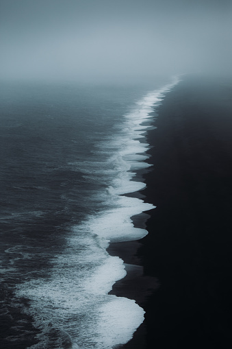 Dramatic view of the black sand beach with ocean during storm and wind in South Iceland