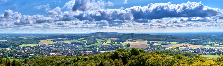 Panorama of villages on the edge of Teutoburg Forest near Osnabruck in Germany above the tree tops and with cloudy sky