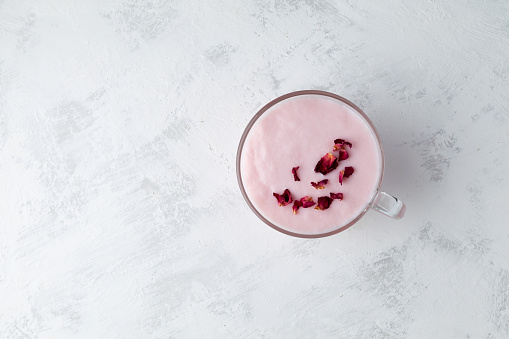 Pink kefir or Ayran, decorated with rose petals. Fermented milk drink. Diet drink for weight loss. Buttermilk from yogurt. Top view, selective focus, copy space.