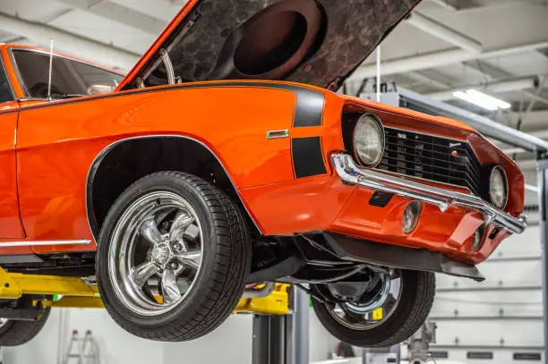 orange muscle car on lift hood open