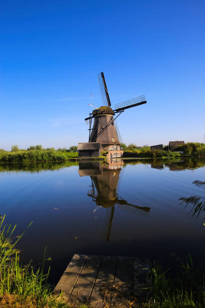 istock View over dutch water canal on old windmills on green meadow against deep blue cloudless summer sky in rural countryside 1340278080