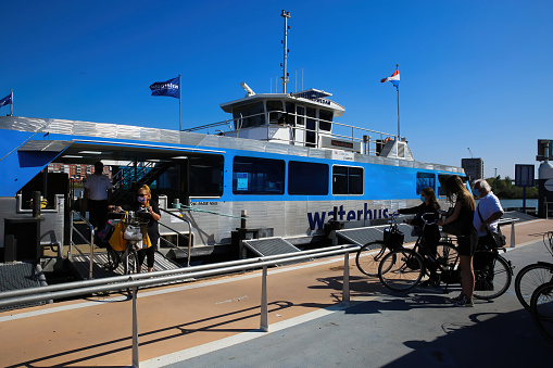 Dordrecht, Netherlands - July 9. 2021: View on waterbus station with boat and people boarding for transportation on old maas river in summer