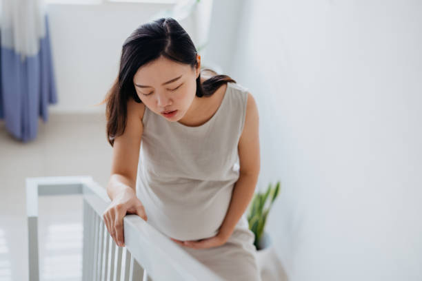 Tired pregnant woman climbing stairs Image of an Asian Chinese pregnant woman feeling pain and tired while climbing stairs pregnant woman stock pictures, royalty-free photos & images