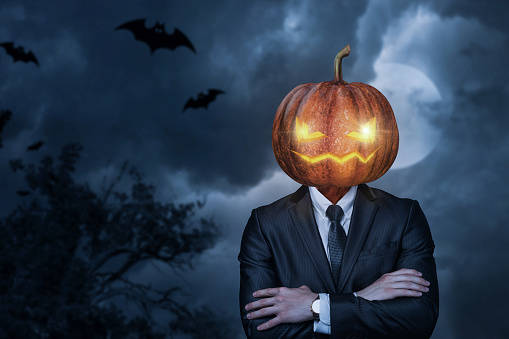 Business man with pumpkin head for halloween on blurred background.