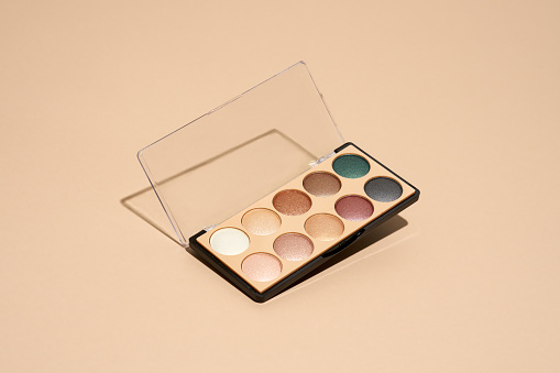 Make-up palette floating over a beige background. Professional multicolor eye shadow make-up palette. Cosmetic products