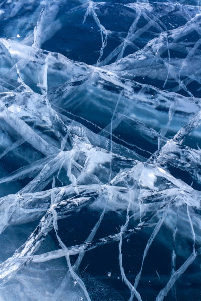 istock Natural thick clear ice with deep cracks. Blue transparent ice with white cracks. Vertical. 1340287583
