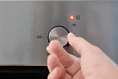 Picture about energy consumption, a man's hand turning an oven thermostat