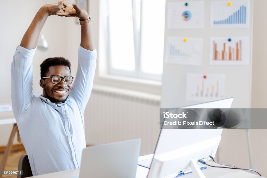 Man Stretches At Office Desk Businessman stretching at his desk in his office Exercising Stock Photo