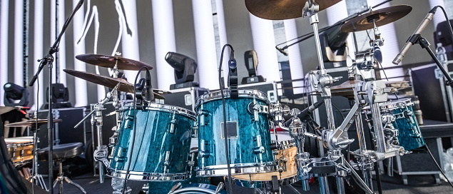Close-up view of professional drum set on stage. Musical instruments assembled with sound equipment prepared for outdoors performance on open-air festival.