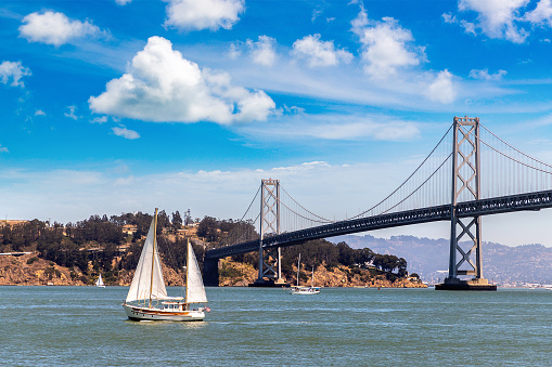 Sailing yacht against Oakland Bay Bridge in San Francisco, California, USA