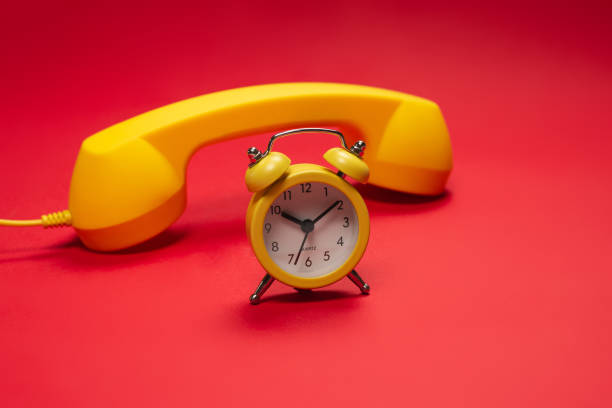 istock Time to call. Yellow handset and alarm clock on a red background. 1340292847